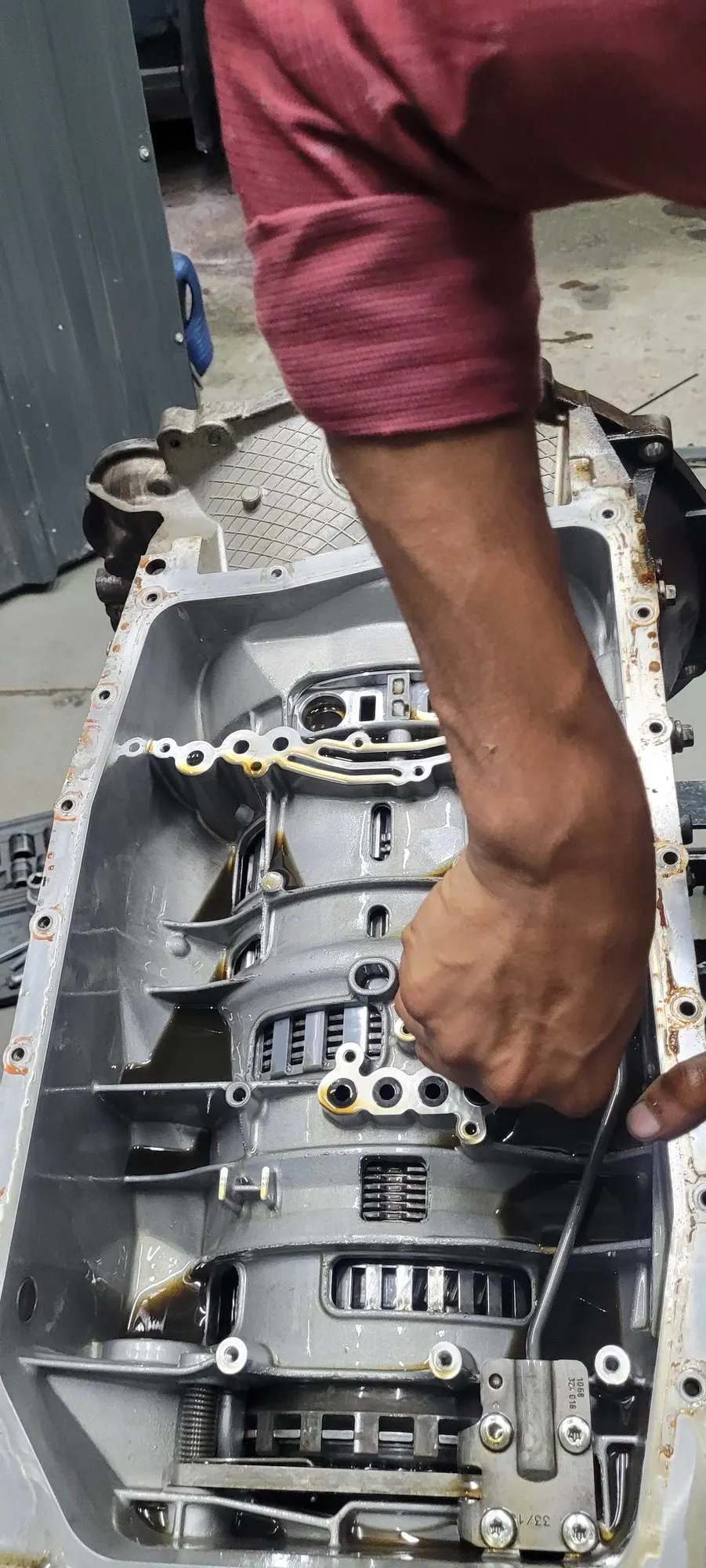 Technician working inside an open automatic gearbox with the valve body removed