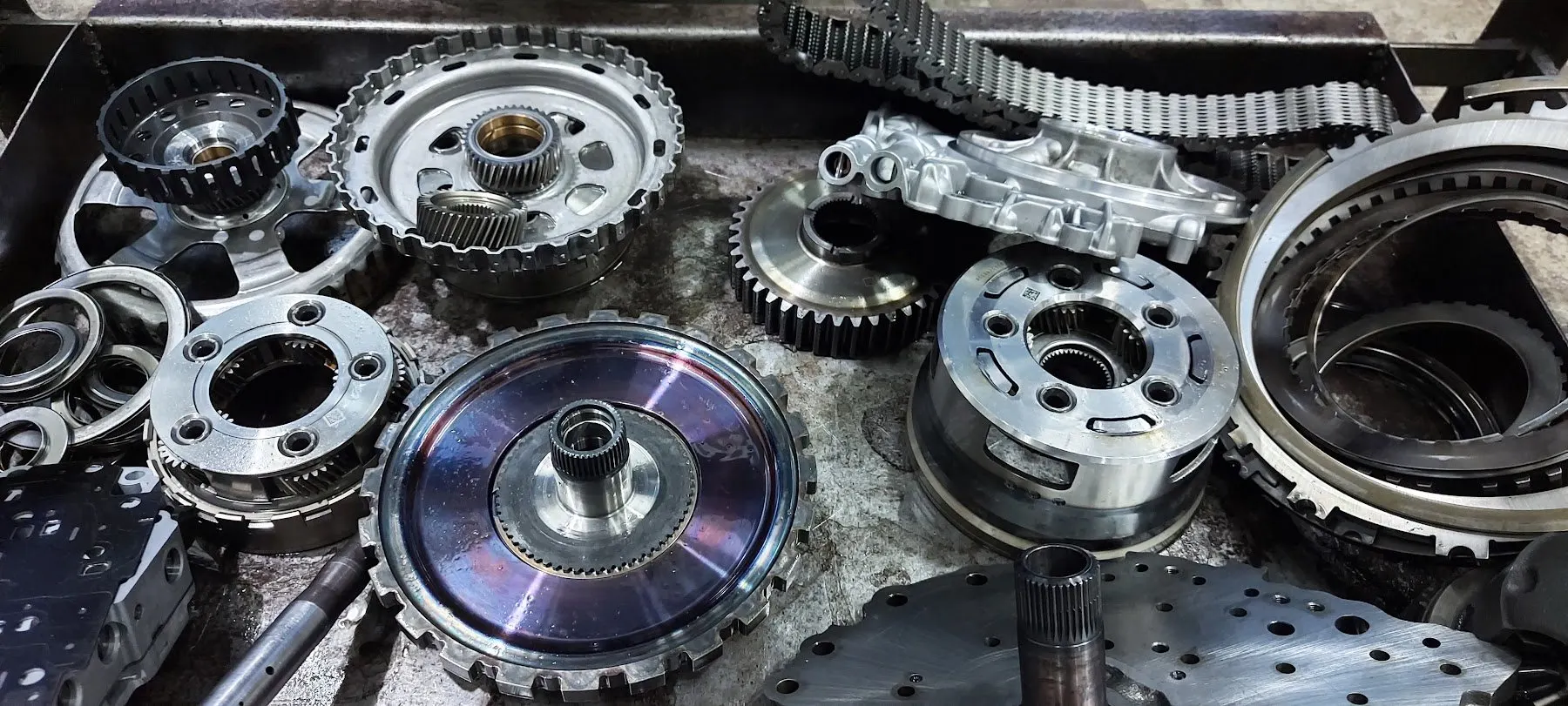 Automatic transmission internals laid out during a teardown: planetary gear sets, clutch drums and hubs